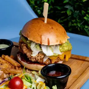Burger au poulet avec guacamol, frites, salades et sauce